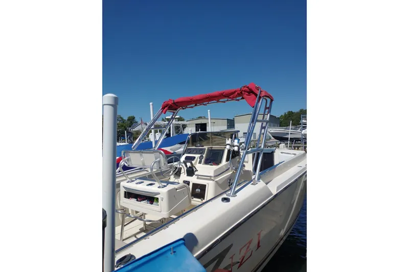Slide: The Image of 1990 Donzi F-33 boat with red canopy, docked at marina under clear blue sky. - 3