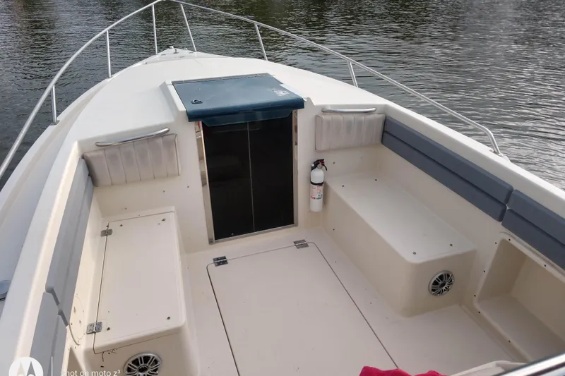 Slide: The Image of 1990 Donzi F-33 boat interior with seating, storage, and safety equipment on calm water. - 4