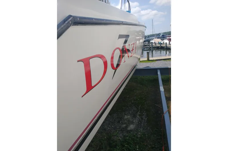 Slide: The Image of 1990 Donzi F-33 boat with red lettering, docked near a marina. - 7