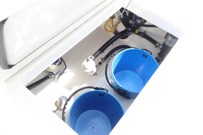 Slide: The Image of 2026 Regulator 25 boat storage compartment with blue buckets and plumbing components. - 6