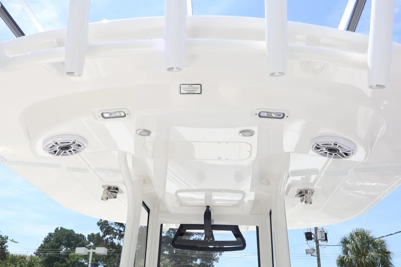 Slide: The Image of 2026 Regulator 25 boat T-top with speakers and rod holders against blue sky. - 9