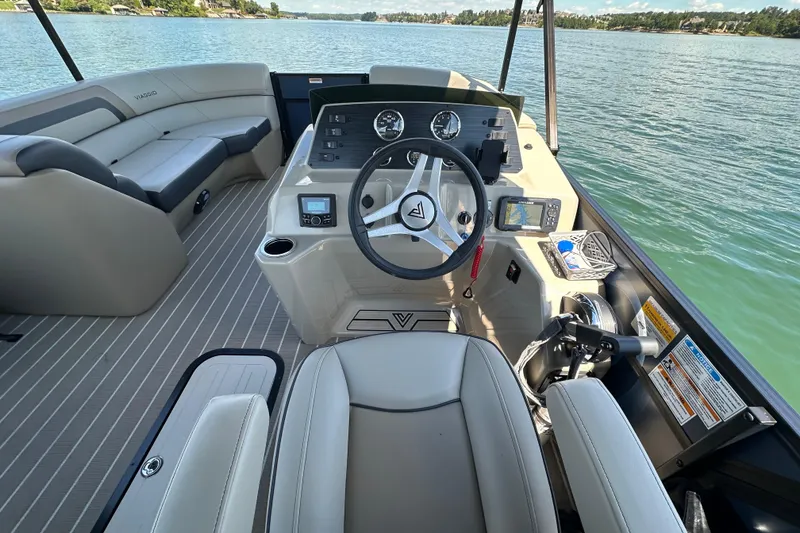 Slide: The Image of 2023 Viaggio 22U boat interior with steering wheel, dashboard, and seating on a lake. - 11