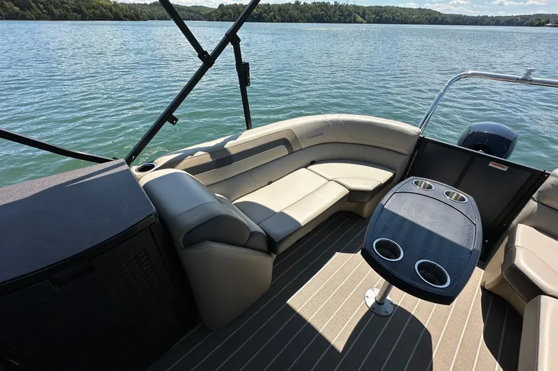 Slide: The Image of Luxurious 2023 Viaggio 22U pontoon boat interior with plush seating and cupholders on a serene lake. - 15
