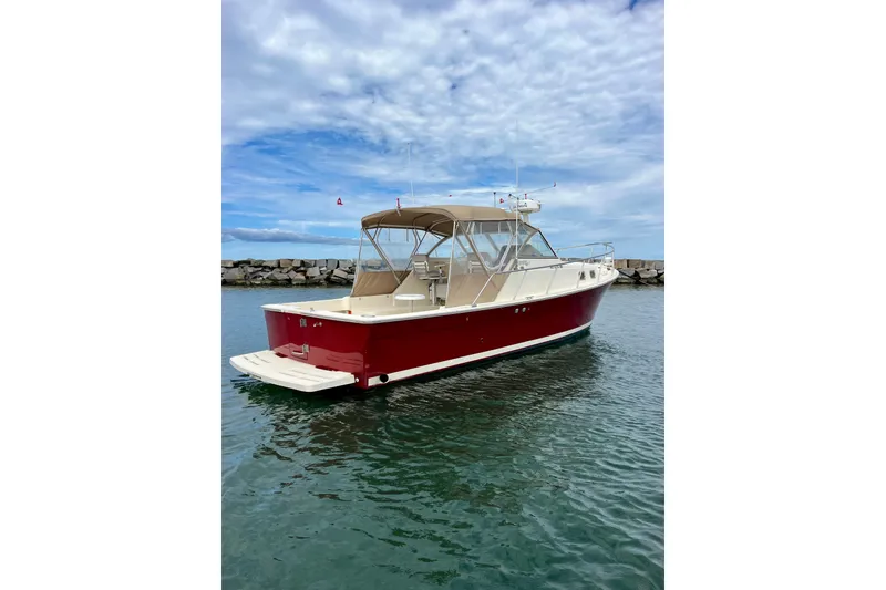 Slide: The Image of 2005 Mainship Pilot 30-II boat with red hull on calm water, under a cloudy sky. - 11