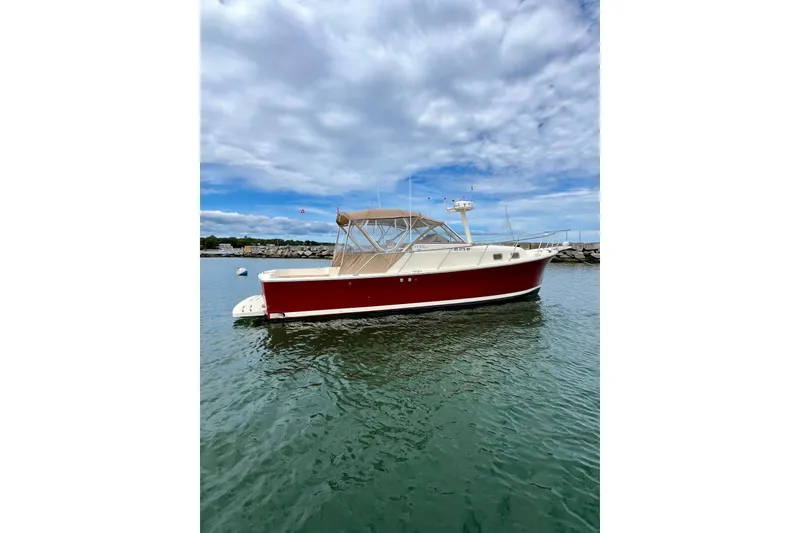Slide: The Image of 2005 Mainship Pilot 30-II boat with red hull on calm water under cloudy sky. - 12