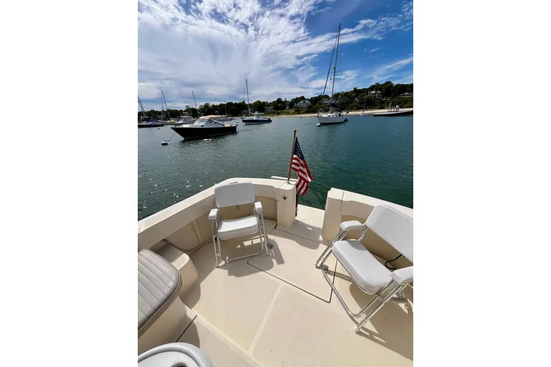 Slide: The Image of 2005 Mainship Pilot 30-II boat deck with chairs, American flag, and scenic harbor view. - 15