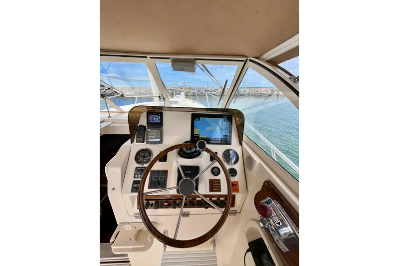 Slide: The Image of 2005 Mainship Pilot 30-II helm with navigation instruments and steering wheel, docked by the water. - 20