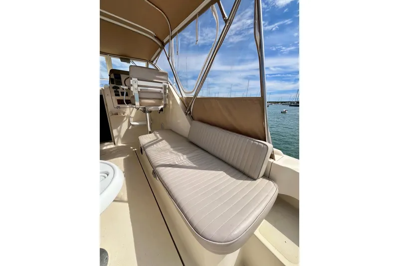 Slide: The Image of 2005 Mainship Pilot 30-II boat interior with beige seating and helm, docked by the water. - 26