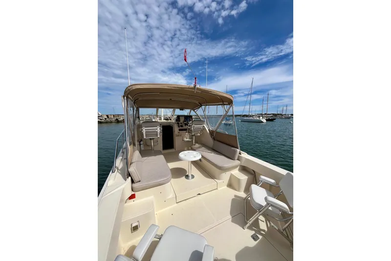 Slide: The Image of 2005 Mainship Pilot 30-II boat with spacious deck, seating, and canopy under a blue sky. - 27