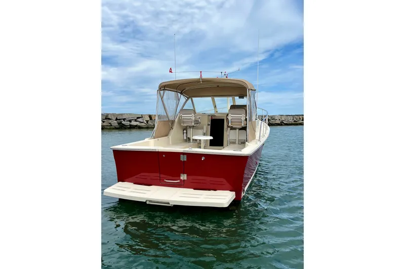 Slide: The Image of 2005 Mainship Pilot 30-II boat with red hull, docked in calm waters. - 3
