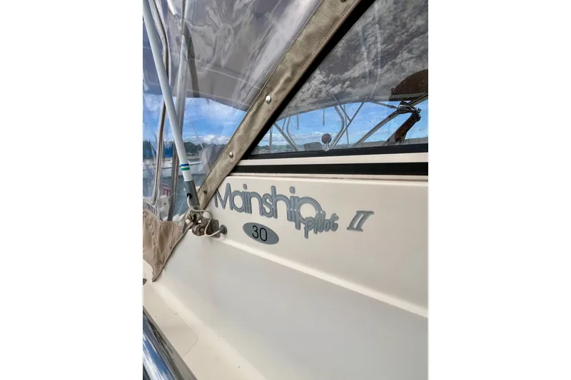 Slide: The Image of 2005 Mainship Pilot 30-II boat with clear canopy and logo detail. - 32