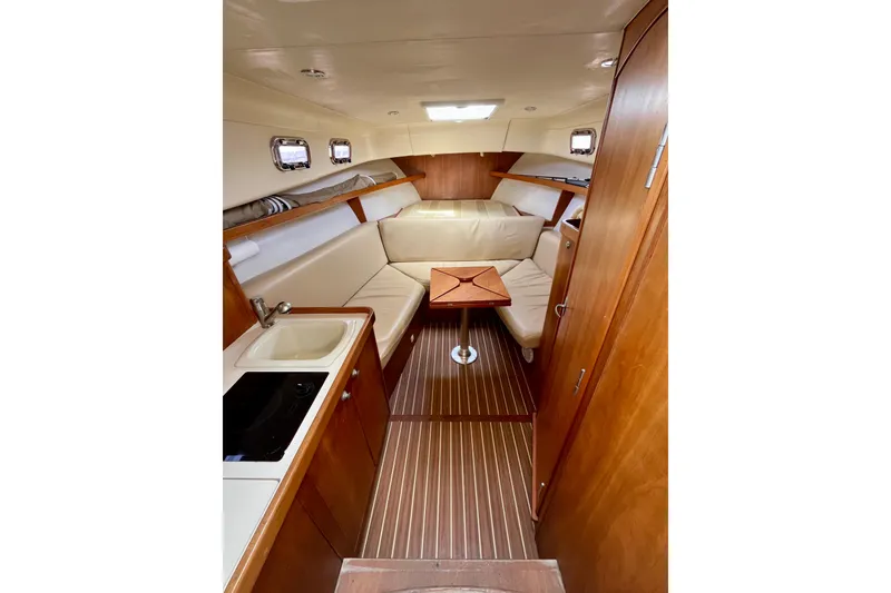 Slide: The Image of 2005 Mainship Pilot 30-II cabin interior with wood finish, kitchenette, and seating area. - 34