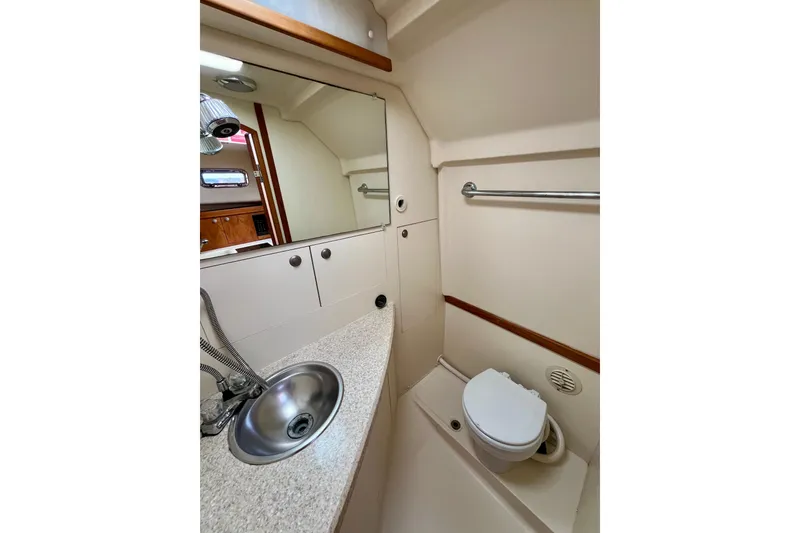 Slide: The Image of 2005 Mainship Pilot 30-II boat bathroom with sink, mirror, and toilet. - 39