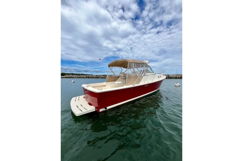 Slide: The Image of 2005 Mainship Pilot 30-II boat with red hull on calm water under cloudy sky. - 4