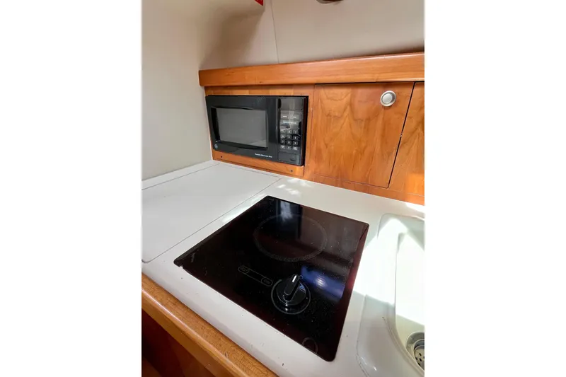 Slide: The Image of 2005 Mainship Pilot 30-II galley with microwave and stovetop. - 48