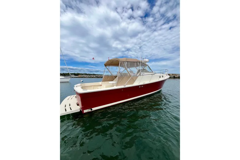 Slide: The Image of 2005 Mainship Pilot 30-II boat with red hull, docked under a cloudy sky. - 5