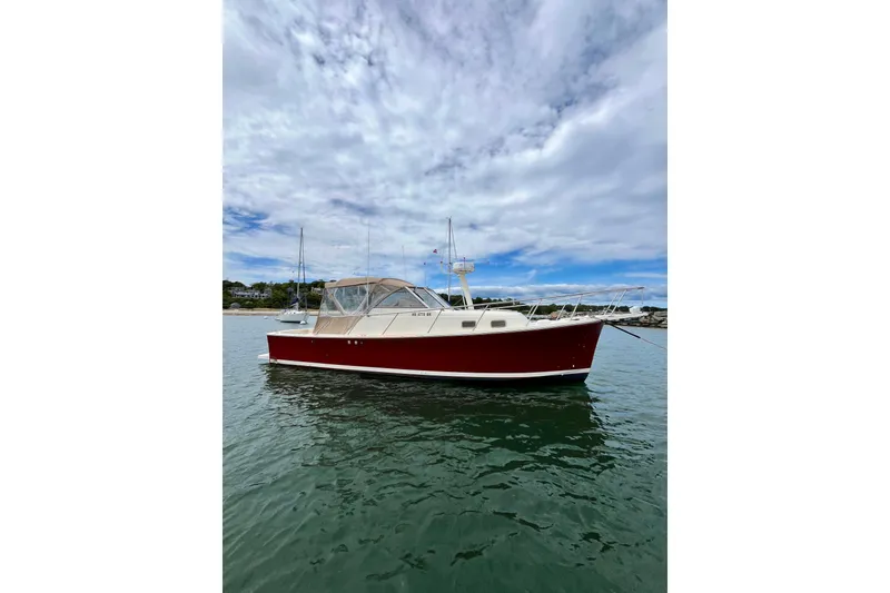 Slide: The Image of 2005 Mainship Pilot 30-II boat with red hull on calm water under cloudy sky. - 6