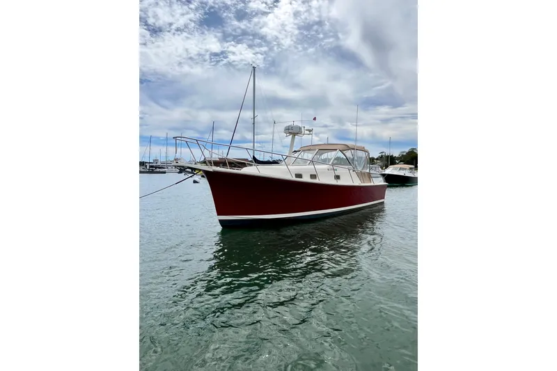 Slide: The Image of 2005 Mainship Pilot 30-II boat with red hull docked on calm water. - 7