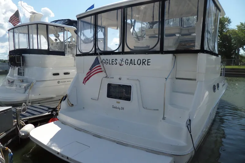 Slide: The Image of 2000 Sea Ray 380 Aft Cabin yacht docked, featuring American flag and enclosed deck. - 3