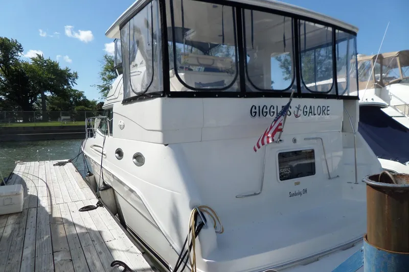 Slide: The Image of 2000 Sea Ray 380 Aft Cabin yacht docked, featuring "Giggles & Galore" name and American flag. - 4