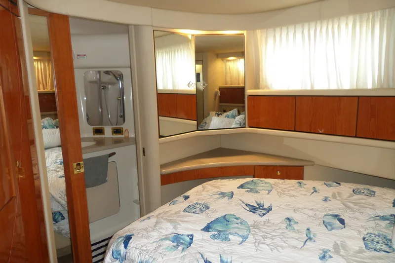 Slide: The Image of 2000 Sea Ray 380 Aft Cabin interior with bed, wooden cabinets, and bathroom. - 61