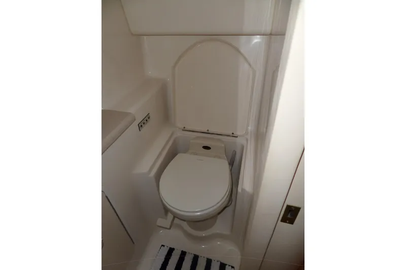 Slide: The Image of 2000 Sea Ray 380 Aft Cabin bathroom with compact toilet and striped rug. - 69