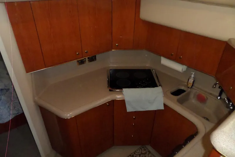 Slide: The Image of 2000 Sea Ray 380 Aft Cabin kitchen with wooden cabinets and compact countertop. - 73