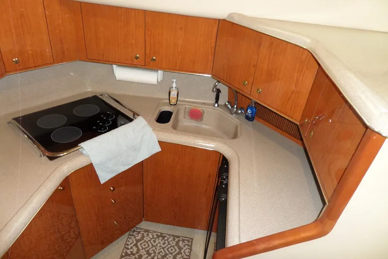 Slide: The Image of 2000 Sea Ray 380 Aft Cabin kitchen with stove, sink, and wooden cabinets. - 74