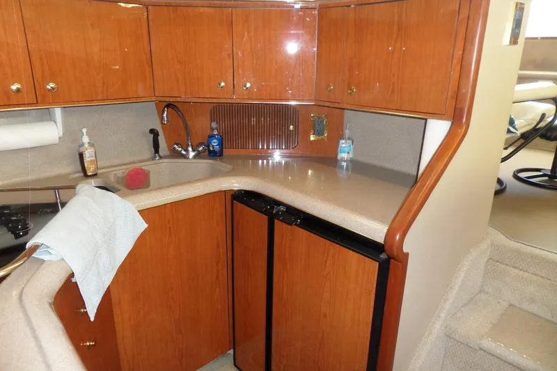 Slide: The Image of 2000 Sea Ray 380 Aft Cabin kitchen with wood cabinets and compact appliances. - 75