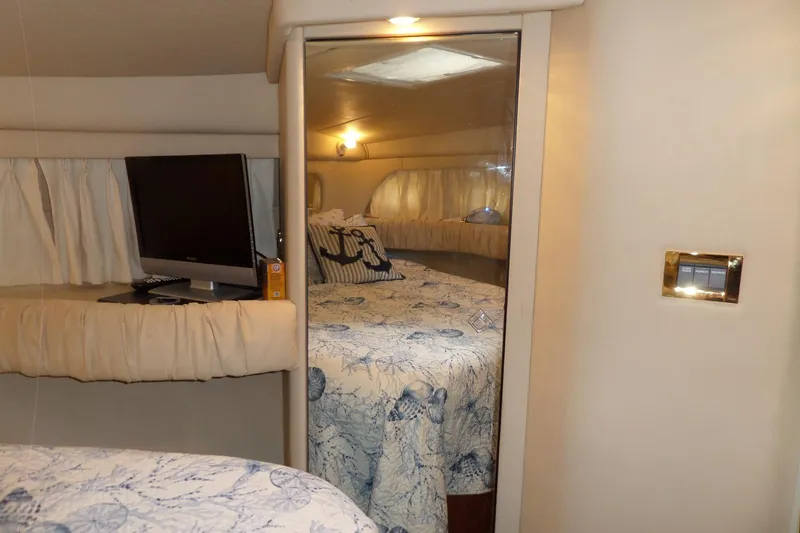 Slide: The Image of Interior of 2000 Sea Ray 380 Aft Cabin with cozy bed and TV setup. - 84