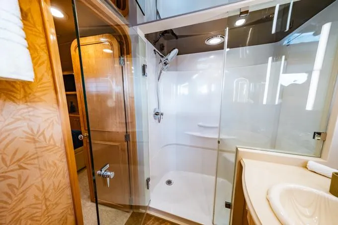Slide: The Image of Luxurious bathroom in a 1995 Hatteras Motor Yacht with glass shower and wooden accents. - 36