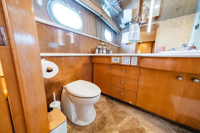 Slide: The Image of Luxurious bathroom in a 1995 Hatteras Motor Yacht with wooden cabinetry and porthole window. - 32