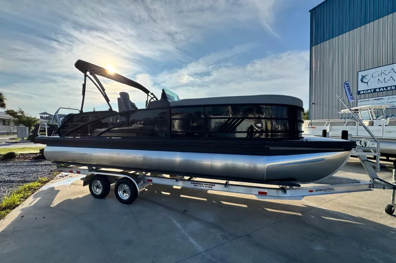 Slide: The Image of 2026 Bennington 24 MSB pontoon boat on trailer, parked outdoors under a clear sky. - 4