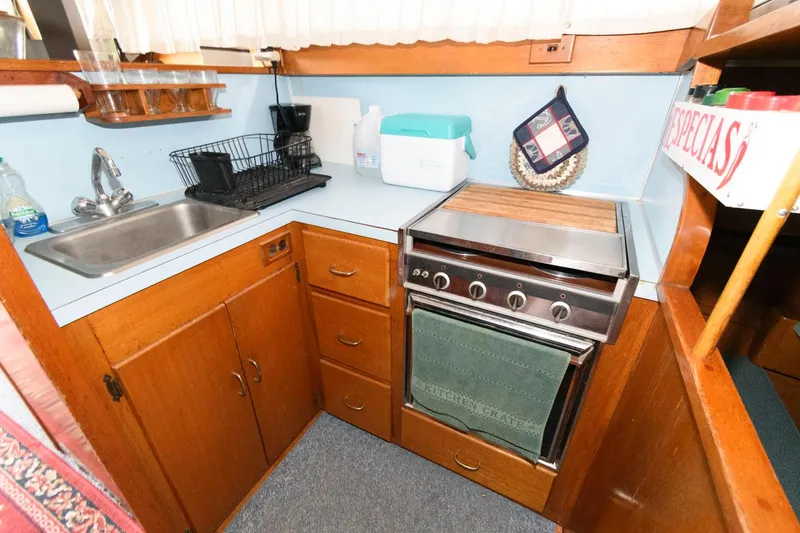 Slide: The Image of 1977 Pequod 34 Sportfish boat kitchen with sink, stove, and storage cabinets. - 21