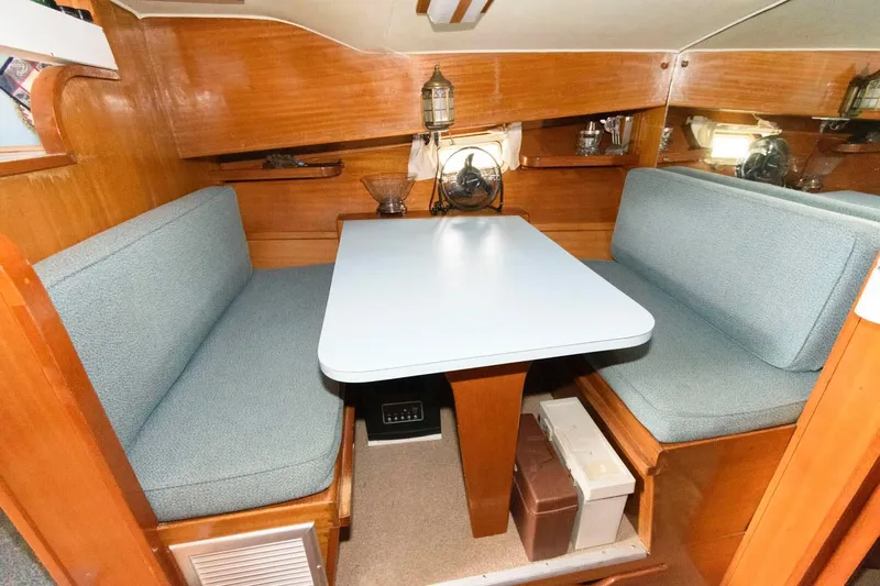Slide: The Image of 1977 Pequod 34 Sportfish boat interior dining area with blue cushioned seating and wooden finish. - 25