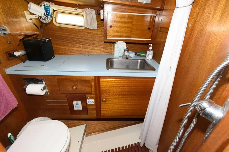Slide: The Image of 1977 Pequod 34 Sportfish boat bathroom with sink, toilet, wooden cabinets, and shower. - 27