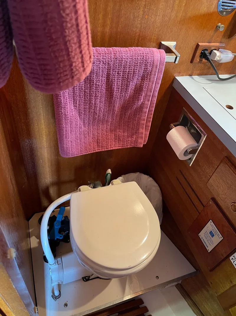Slide: The Image of 1977 Pequod 34 Sportfish boat bathroom with toilet, sink, and pink towel. - 39