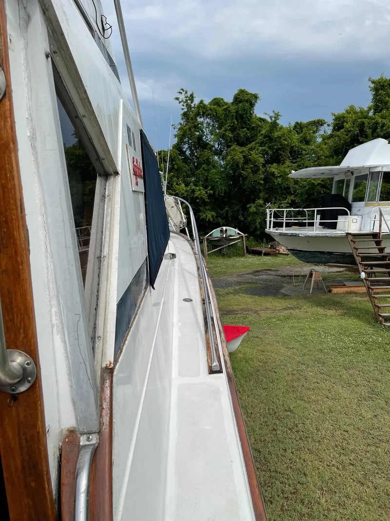 Slide: The Image of 1977 Pequod 34 Sportfish boat on land near trees and another boat. - 8