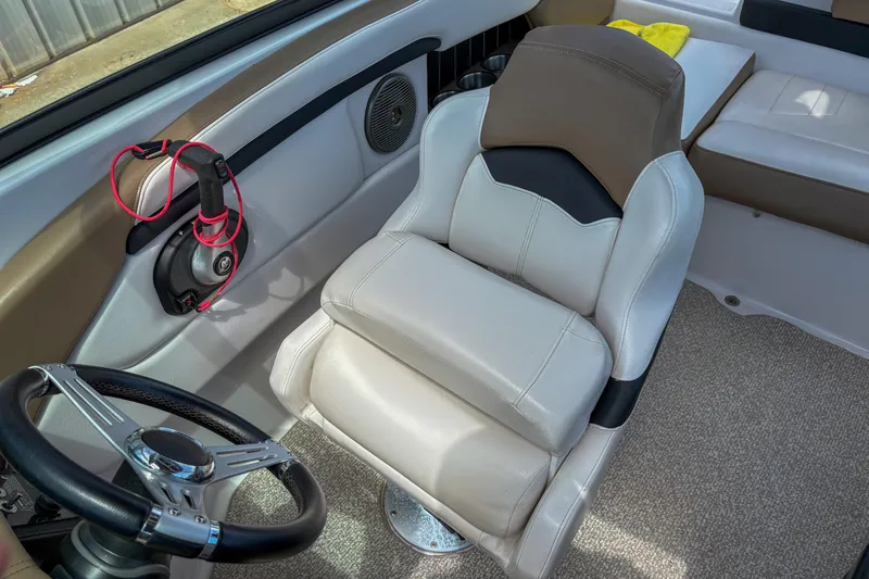 Slide: The Image of 2016 Four Winns H210 boat interior with steering wheel and cushioned seat. - 7