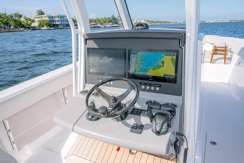 Slide: The Image of 2026 Jupiter 340LS boat dashboard with dual navigation screens and steering wheel on open water. - 31