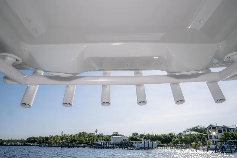Slide: The Image of Underneath view of 2026 Jupiter 340LS boat with rod holders, overlooking a sunny waterfront. - 34