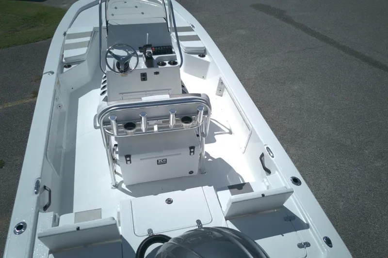 Slide: The Image of 2026 Froniter 2104 boat interior with steering console and seating, parked on pavement. - 7