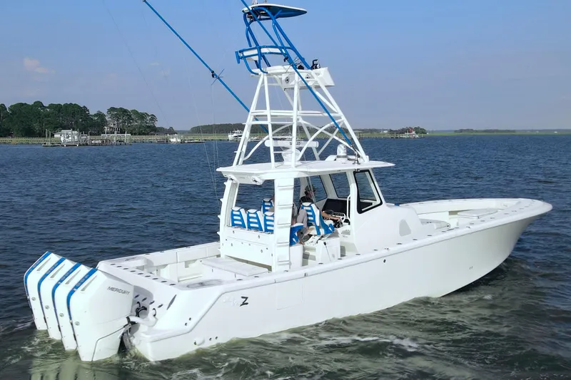 Slide: The Image of 2024 SeaVee 420Z boat cruising on a calm lake with multiple outboard engines. - 2