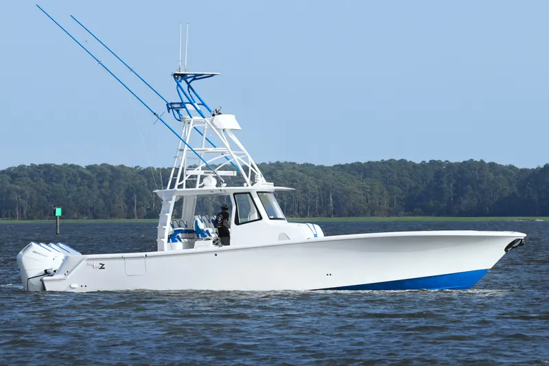 Slide: The Image of 2024 SeaVee 420Z boat cruising on a calm lake with forested shoreline. - 3