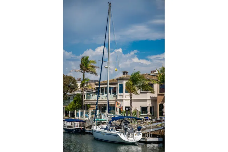 Slide: The Image of 2005 Catalina 36 MkII sailboat docked near waterfront homes, under a clear blue sky. - 3