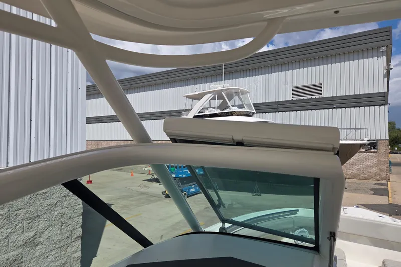 Slide: The Image of 2023 Pursuit DC 266 Dual Console boat near industrial building, showcasing sleek design. - 15