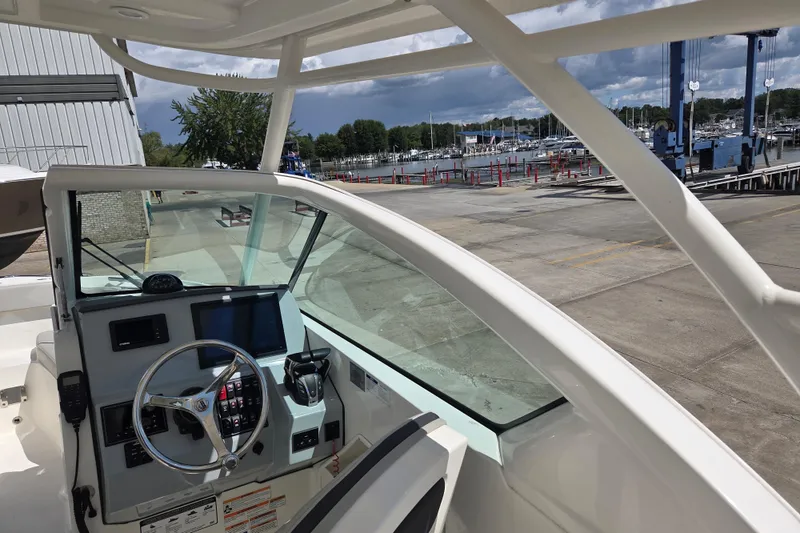 Slide: The Image of 2023 Pursuit DC 266 Dual Console boat interior at marina, featuring steering wheel and control panel. - 16