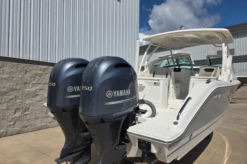 Slide: The Image of 2023 Pursuit DC 266 Dual Console boat with twin Yamaha 150 engines, docked outdoors. - 2