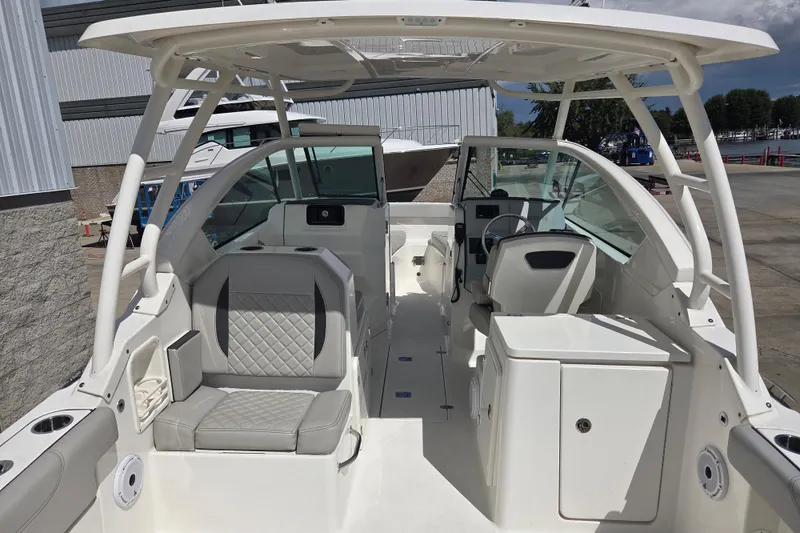 Slide: The Image of 2023 Pursuit DC 266 Dual Console boat interior with seating and helm, docked outdoors. - 6