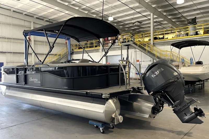Slide: The Image of 2026 Barletta ARIA 22QC pontoon boat interior with stainless steel railings in a warehouse. - 2